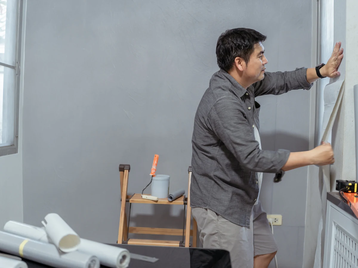 wallpapering-man-applying-wallpaper-surrey-decorators Wallpapering in Surrey by Surrey Decorators, man carefully applying patterned wallpaper to a wall